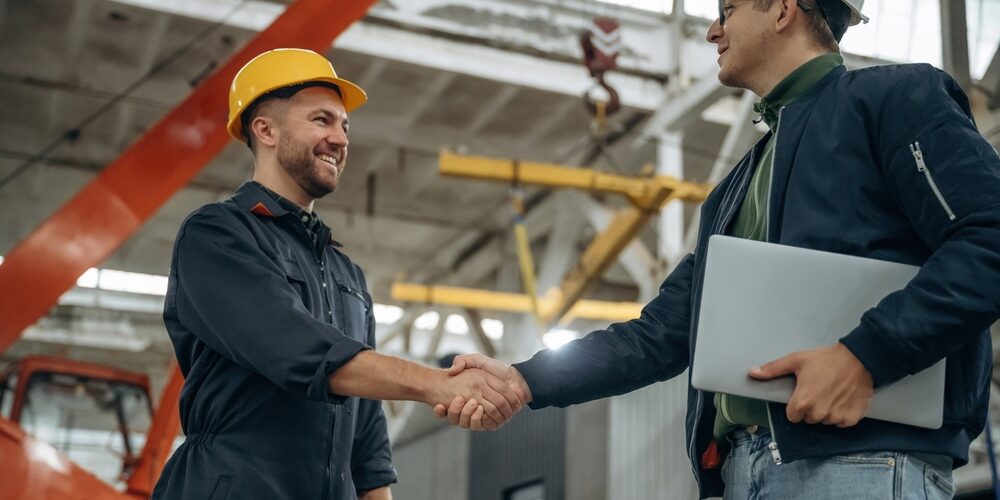 Friendly,Handshake.,Two,Male,Factory,Workers,Are,In,The,Warehouse.